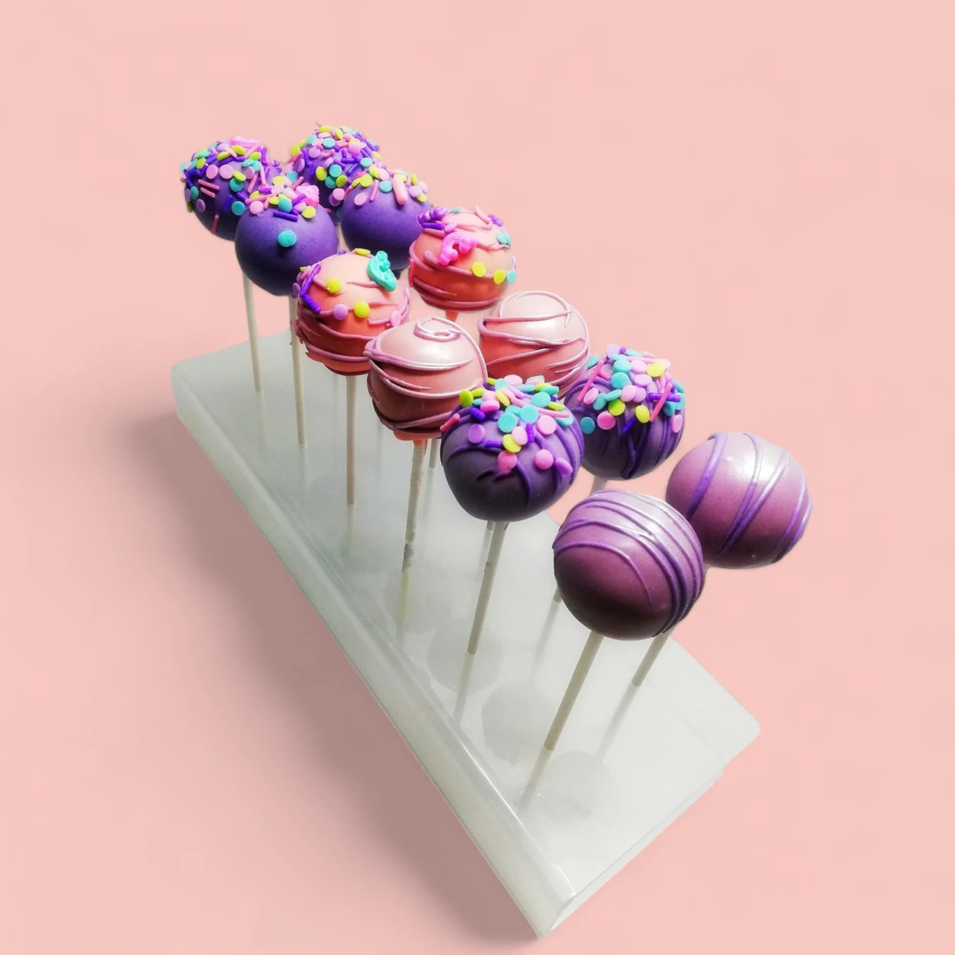 Pink and Purple Cake Pops with Chocolate Drizzle and Sprinkles by Love Bites Cake Hub